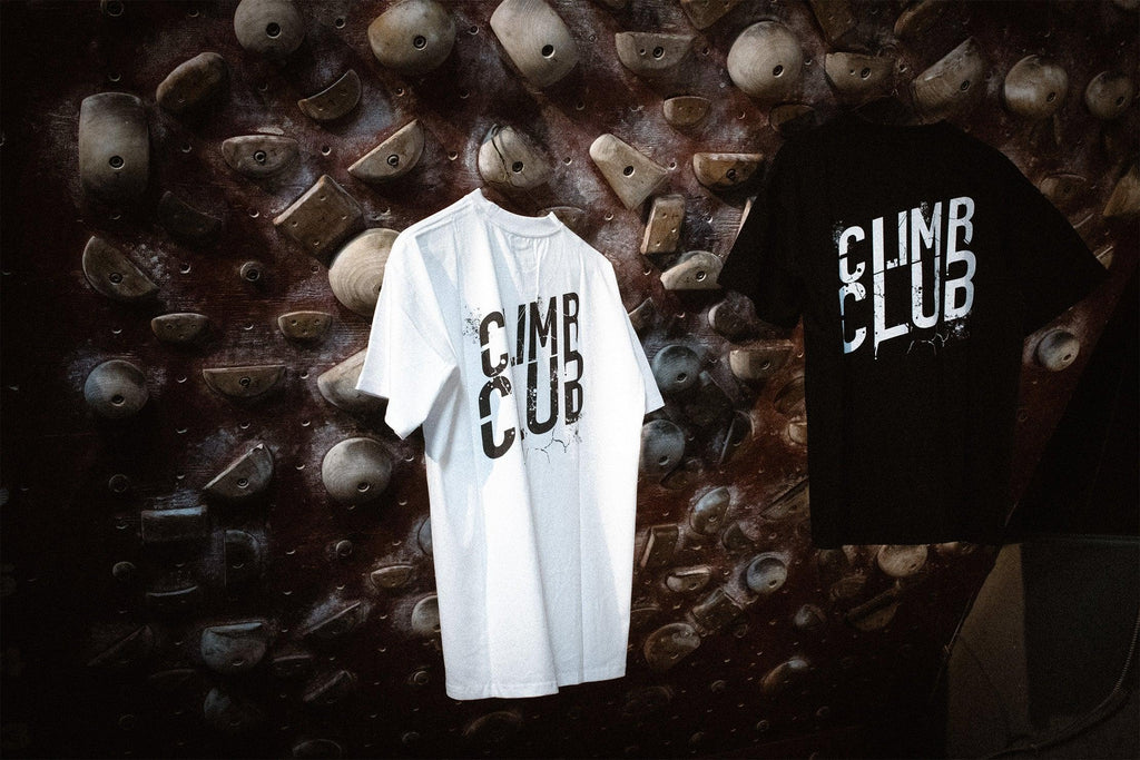 Climb Club graphic t-shirts hanging on indoor climbing wall background