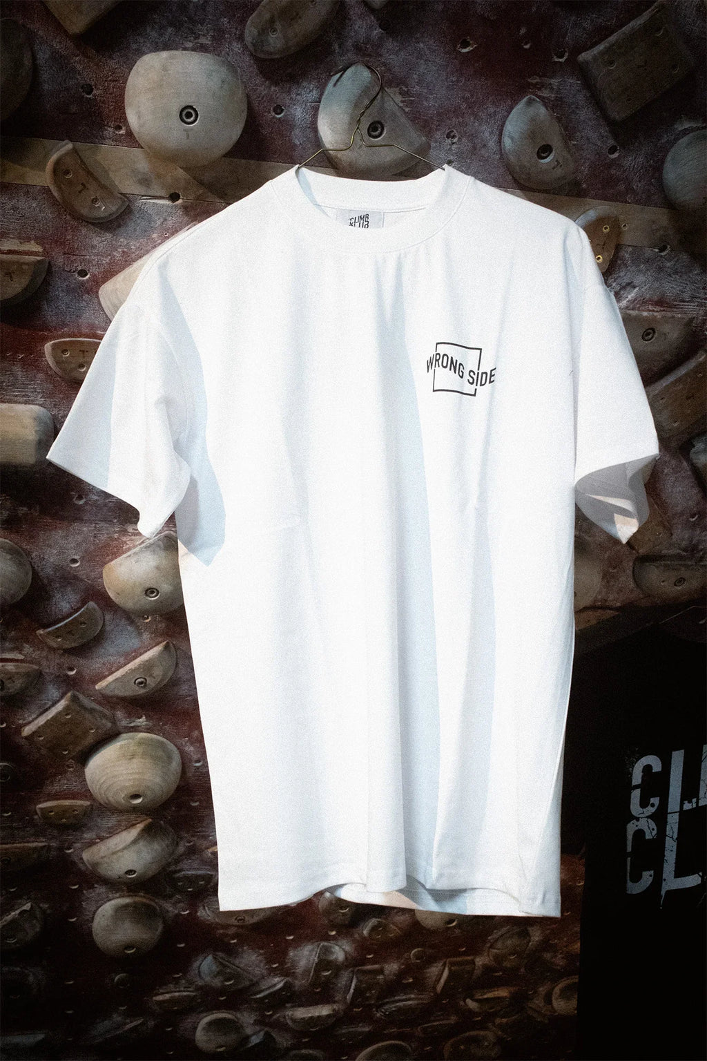 White 'Wrong Side' t-shirt by Climb Club on indoor climbing wall, climbing apparel.